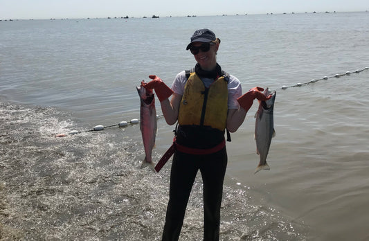 woman in bristol bay, Alaska with a huge dip net and a salmon inside the net