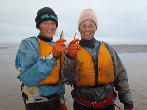 Mom and Daughter holding up rainbow smelt aka cucumber fish after fishing in Bristol Bay Alaska - the Popsie Cucumber Fish Tradition