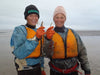 Mom and Daughter holding up rainbow smelt aka cucumber fish after fishing in Bristol Bay Alaska